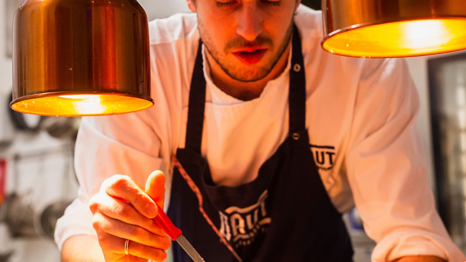 The pass at service: a cook at the steel, tickets in the rail.